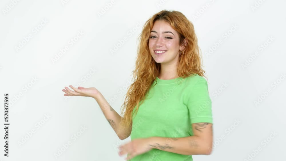 Young redhead woman pointing finger to the side and presenting a product over isolated background Young redhead woman pointing finger to the side and presenting a product over isolated background