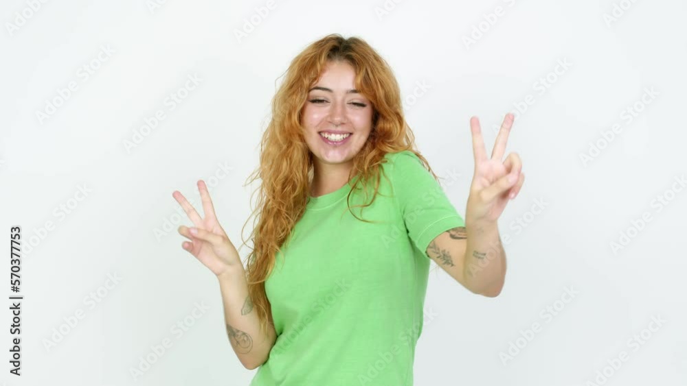 Young redhead woman smiling and showing victory sign with a cheerful face over isolated background Young redhead woman smiling and showing victory sign with a cheerful face over isolated background