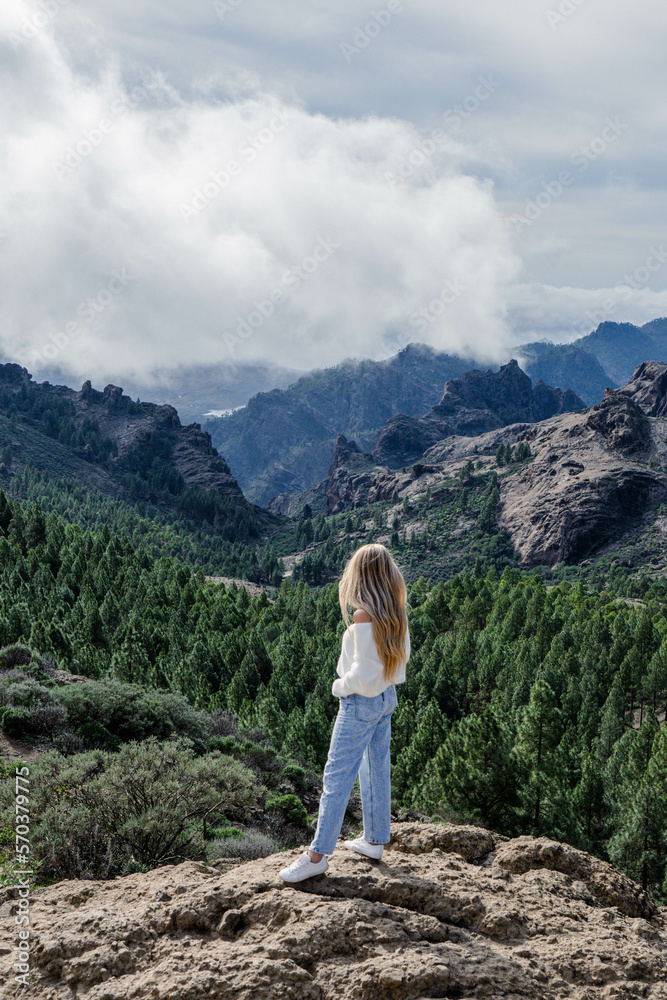 Woman standing at the top of the mountain surrounded by the nature 