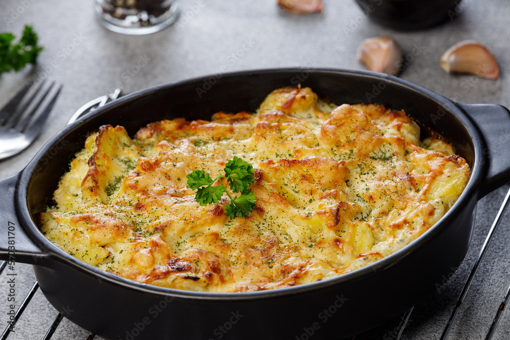Potato casserole with cheese and parsley on stone background. French cuisine, close up Potato casserole with cheese and parsley on stone background. French cuisine, close up