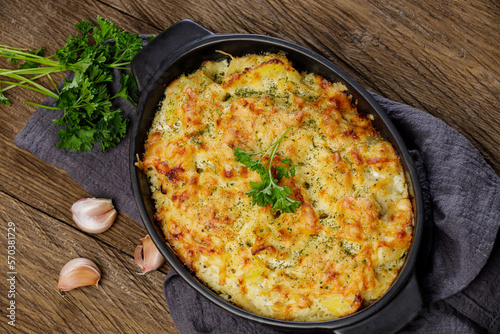 Potato casserole with cheese and parsley on wooden table. French cuisine, top view