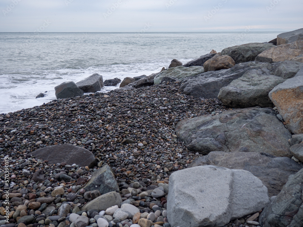 resort in winter. The rocky shore is washed by the waves in cloudy weather. Black Sea coast. The coast of Batumi. Nature in shades of grey.  boring landscape