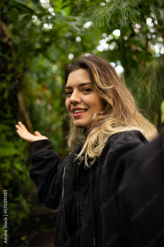 Young beautiful woman taking selfie in forest. She invite to nature.