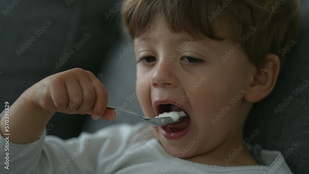 Child eating yogurt with spoon. Close up face of little boy eats nutritious breakfast food Child eating yogurt with spoon. Close up face of little boy eats nutritious breakfast food