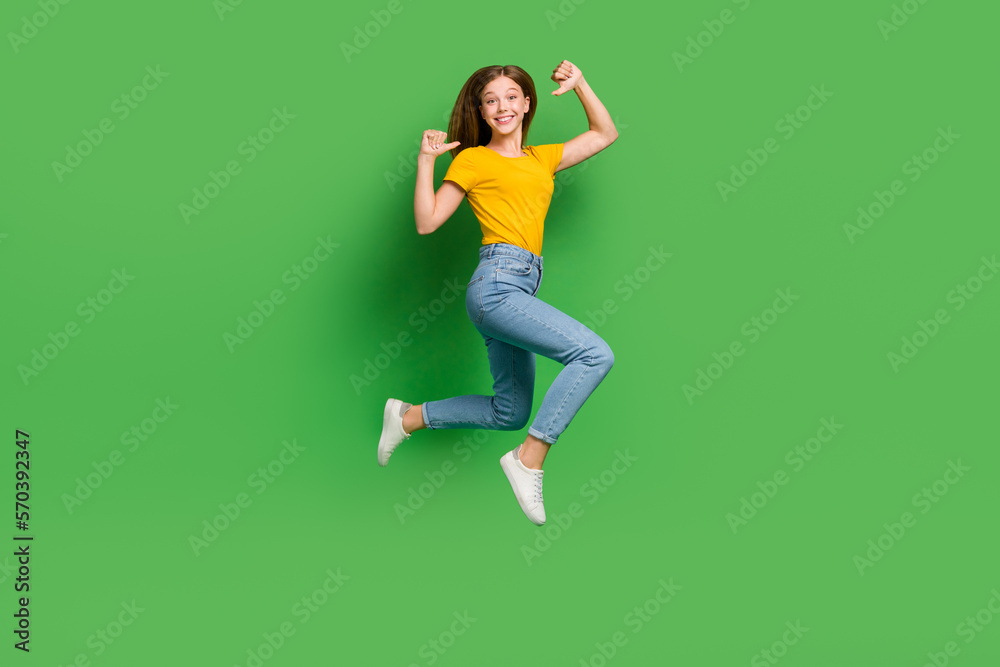Full length portrait of active energetic person jumping indicate thumb fingers herself isolated on green color background Full length portrait of active energetic person jumping indicate thumb fingers herself isolated on green color background