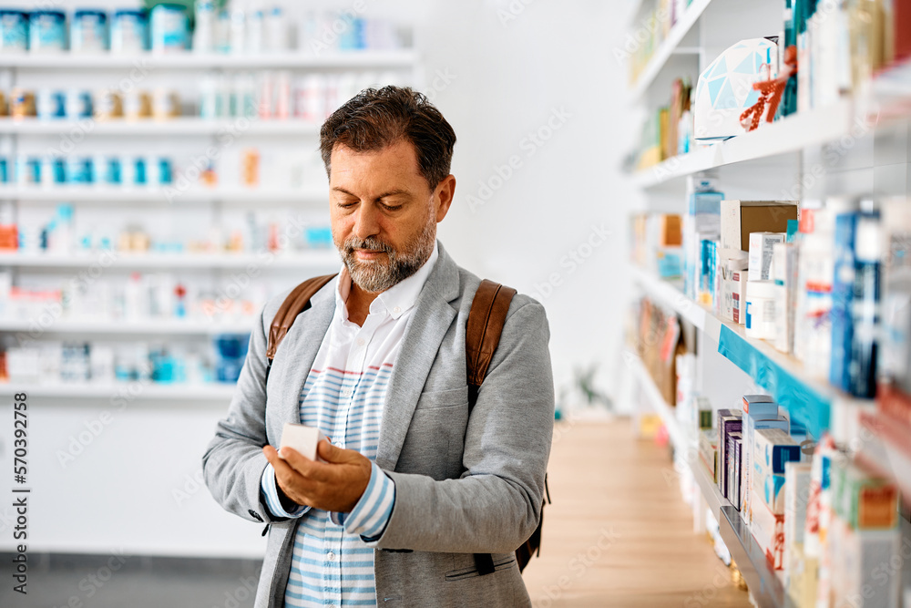 Middle aged man buying medicine in pharmacy.