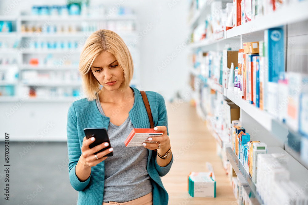 Woman using app on mobile phone while shopping in pharmacy,