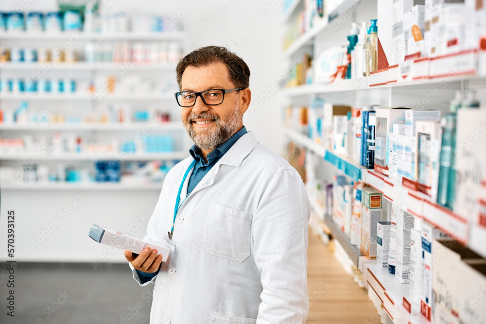 Happy male pharmacist working in drugstore and looking at camera. Happy male pharmacist working in drugstore and looking at camera.