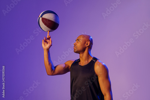 Professional basketball player spinning ball on his finger on studio background © Kostiantyn