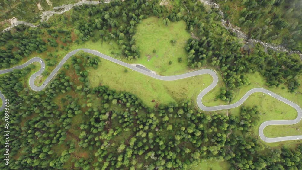 Famous sightseeing serpentine road for tourists among meadows of Giau Pass. Cars drive on Snake Road surrounded by forests of Giau Pass aerial view