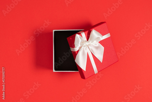 Red gift box, present giftbox red ribbon on red background. Valentine's day. Christmas. Flat lay, top view, copy space