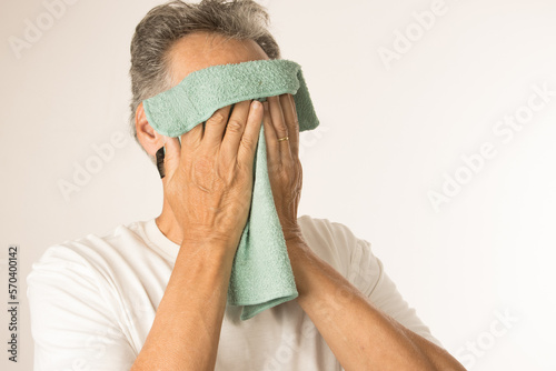 Older man with a warn compress over his eyes for pain relief