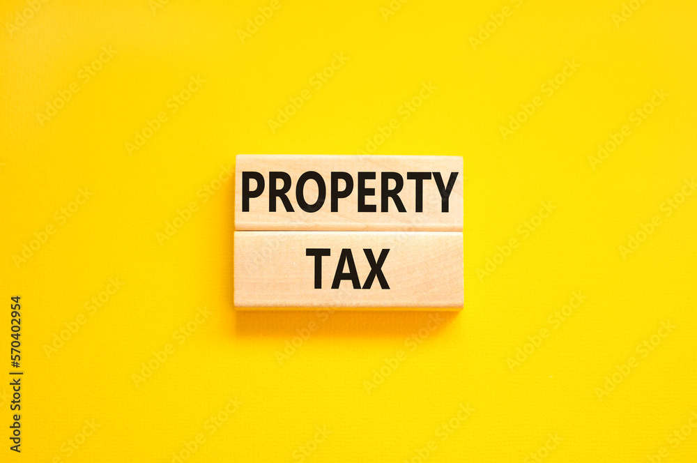 Property tax symbol. Concept words Property tax on wooden blocks. Beautiful yellow table yellow background. Business and property tax concept. Copy space. Property tax symbol. Concept words Property tax on wooden blocks. Beautiful yellow table yellow background. Business and property tax concept. Copy space.