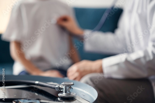 Stethoscope lying on the tablet computer in front of doctor and kid boy patient at the background . Medicine, healthcare concept