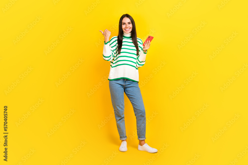 Full length photo of charming adorable positive lady wear trendy outfit demonstrate offer empty space isolated on yellow color background Full length photo of charming adorable positive lady wear trendy outfit demonstrate offer empty space isolated on yellow color background