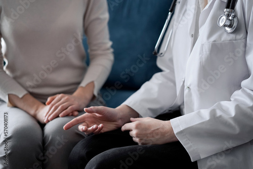 Doctor and patient discussing current health examination while sitting at sofa in clinic office, closeup. Medicine concept