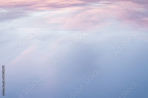 Fototapeta Naklejka Na Ścianę i Meble -  Aerial view from plane on the sea through sky with soft and fluffy pastel pink and blue colored clouds. Sunset background. Nature. sunrise. Instagram toned style