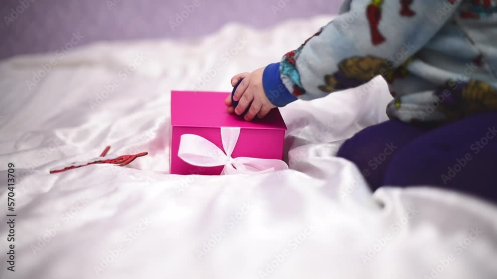 Close-up present pink box and hands of kid playing with blue box with golden rings Close-up present pink box and hands of kid playing with blue box with golden rings