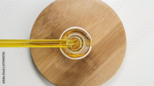 Glass flask with natural oil. White background. Aromatherapy. Oil flows through a glass pipette. Anti-aging and care cosmetics. Top view. 