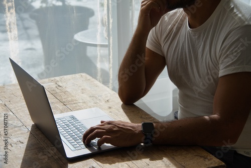 Unrecognizable man searching information on the internet with laptop.