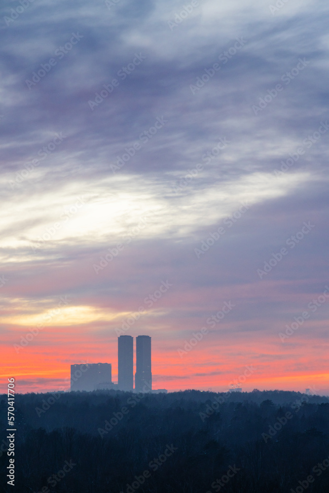 clouds in dawn sky over city park and towers on cold morning