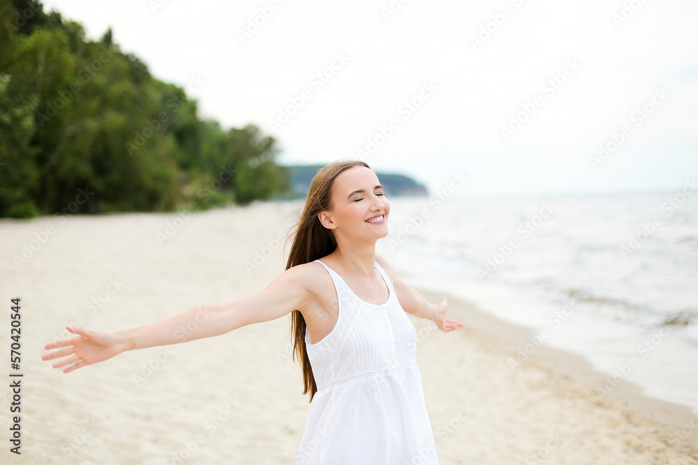 Happy smiling woman in free happiness bliss on ocean beach standing with open hands. Portrait of a multicultural female model in white summer dress enjoying nature Happy smiling woman in free happiness bliss on ocean beach standing with open hands. Portrait of a multicultural female model in white summer dress enjoying nature