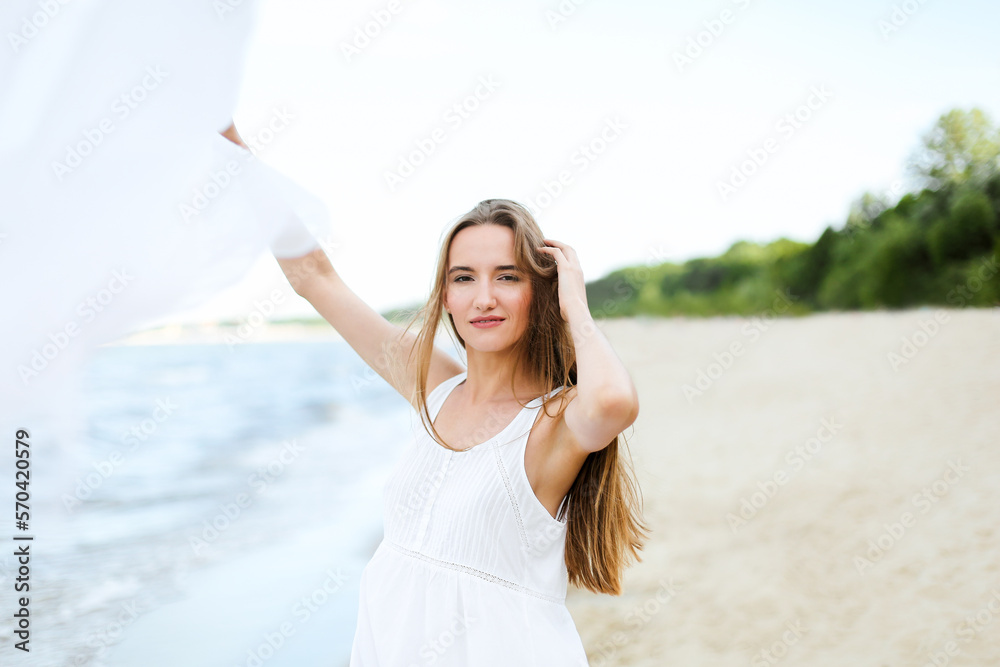 Happy smiling woman in free happiness bliss on ocean beach catching clouds. Portrait of a multicultural female model in white summer dress enjoying nature during travel holidays vacation outdoors Happy smiling woman in free happiness bliss on ocean beach catching clouds. Portrait of a multicultural female model in white summer dress enjoying nature during travel holidays vacation outdoors