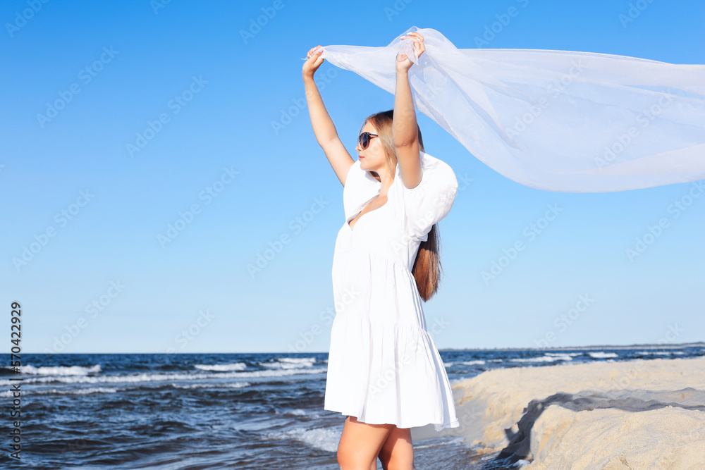 Happy blonde woman is catching clouds and wind with her arms on the ocean beach Happy blonde woman is catching clouds and wind with her arms on the ocean beach