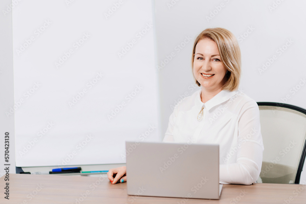 a woman in a white shirt in the office with a meeting board, desktop and laptop a woman in a white shirt in the office with a meeting board, desktop and laptop