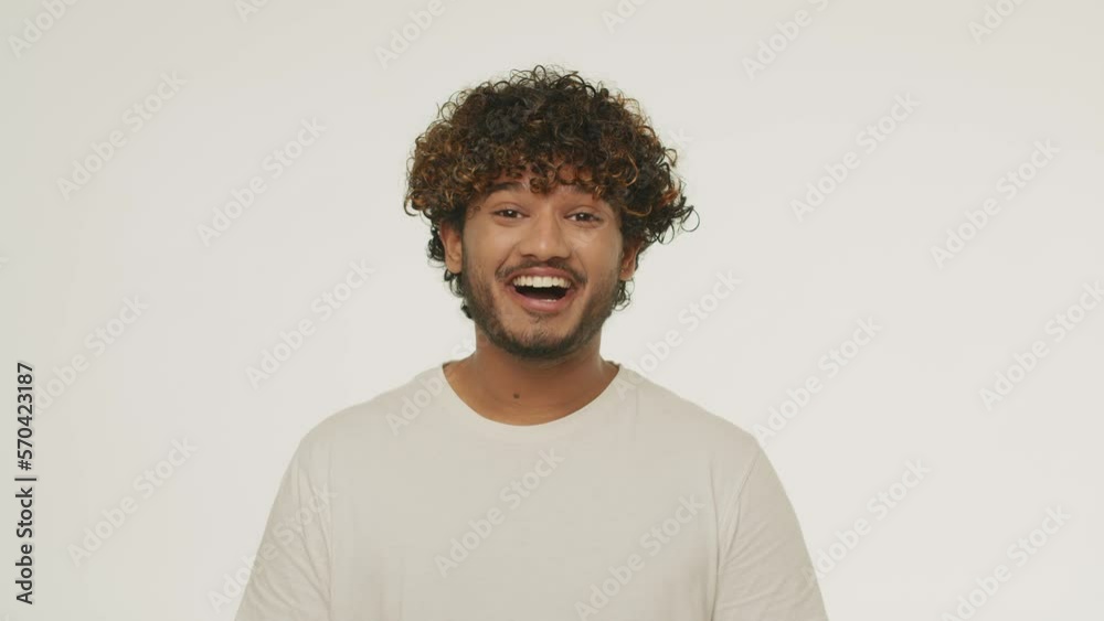 Front view of young man hearing good news. Studio footage of excited guy with surprised smile. Shocked male model laughing on white background Front view of young man hearing good news. Studio footage of excited guy with surprised smile. Shocked male model laughing on white background
