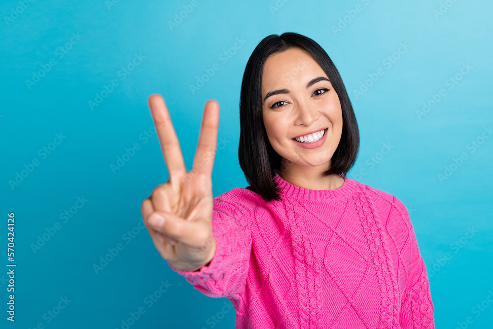 Photo of cheerful nice person beaming smile arm fingers demonstrate v-sign isolated on blue color background Photo of cheerful nice person beaming smile arm fingers demonstrate v-sign isolated on blue color background