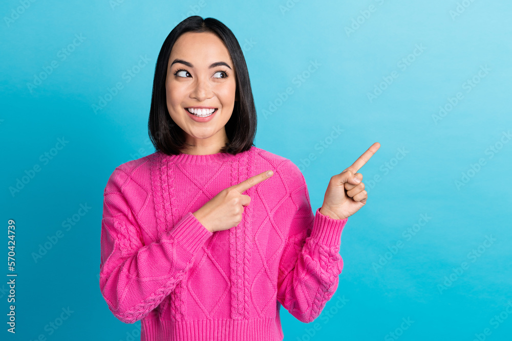 Photo of dreamy cute youngster cheerful woman wear pink knitwear demonstrate fingers look mockup useful information isolated on blue color background Photo of dreamy cute youngster cheerful woman wear pink knitwear demonstrate fingers look mockup useful information isolated on blue color background