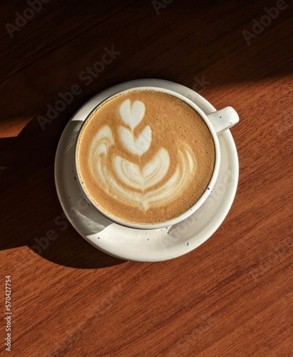 delicious coffee with a beautiful arch in a white cup in the rays of warm sun