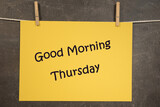 Napis Good morning Thursday na wiszącej żółtej kartce na ciemnym tle