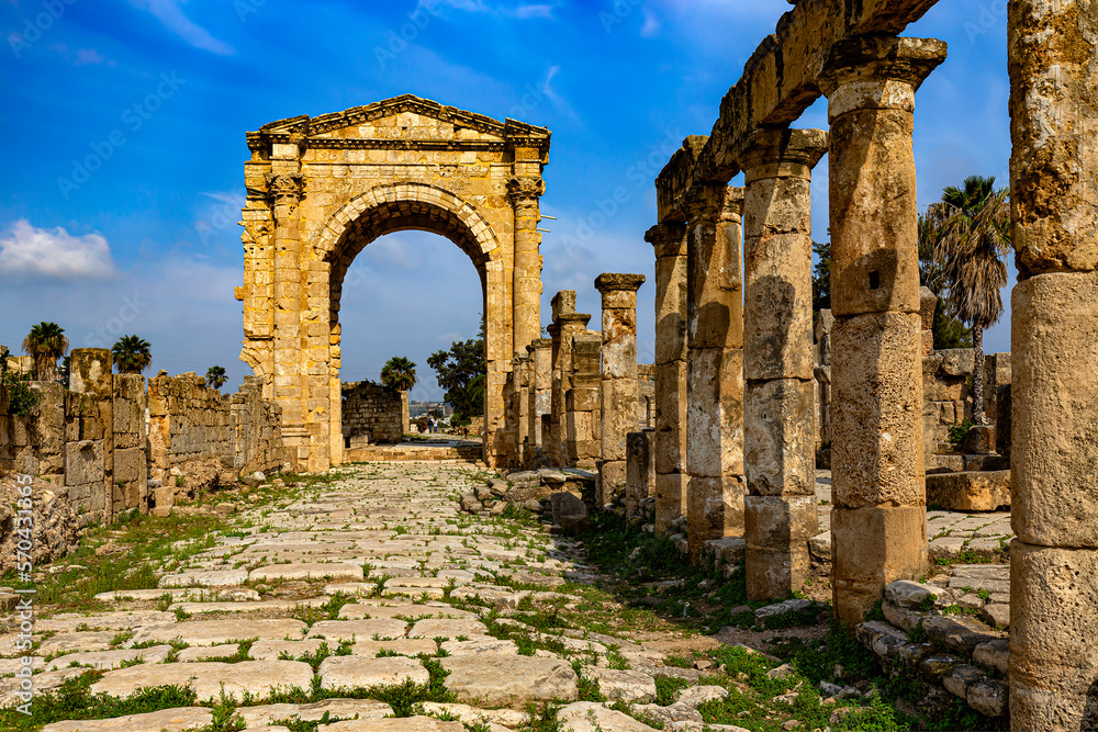 Lebanon. Ancient Tyre (UNESCO World Heritage Site) - Al-Bass Archaeological Site. Paved Roman road and the triumphal arch of Hadrian in the background