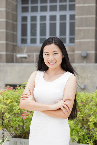 Portrait of successful Asian businesswoman standing with arms crossed standing in front of the office building