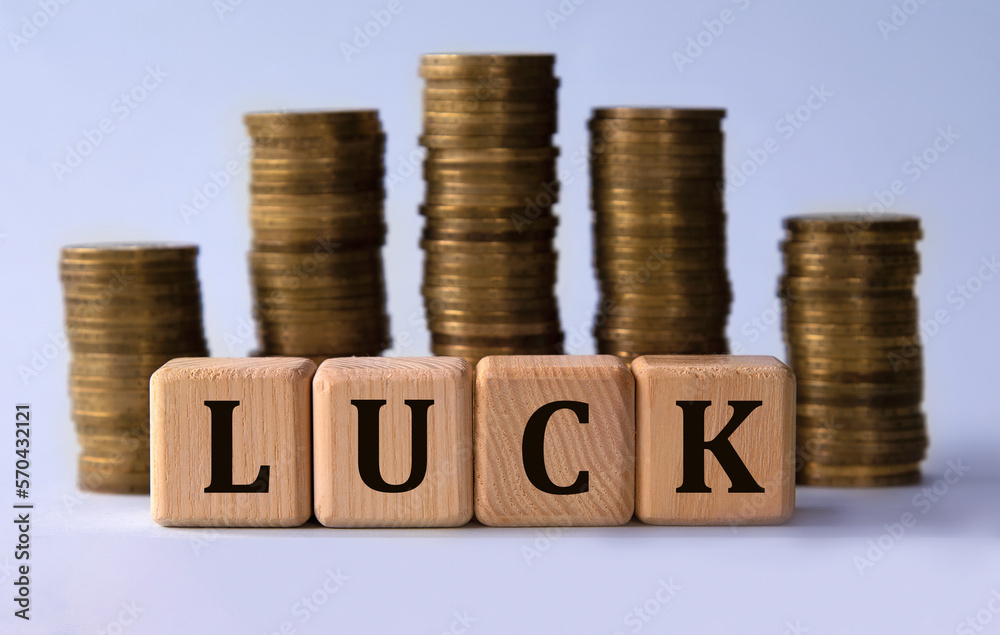 LUCK - acronym on wooden cubes on the background of stacks of coins LUCK - acronym on wooden cubes on the background of stacks of coins