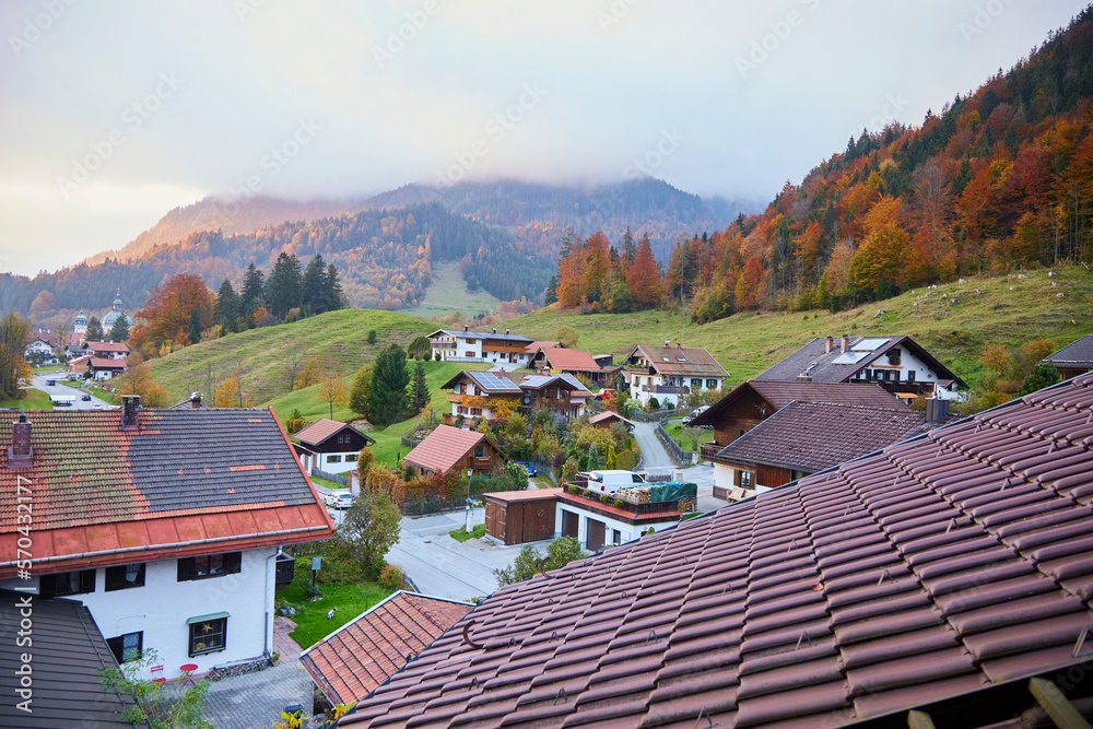 Fototapeta premium View of the Bavarian Alps, houses, village, trees, mountain haze and autumn forest. View from window.
