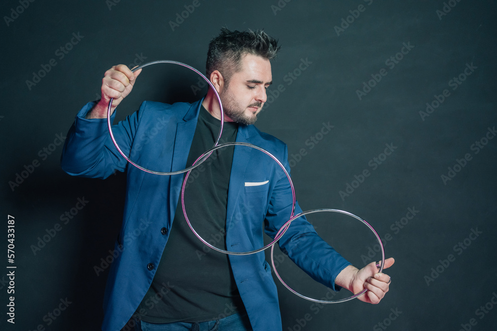 Young magician in the dark holding with both hands a set of three linked metal rings.