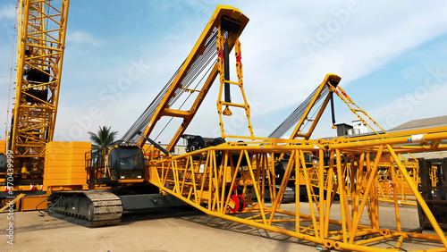 Two big yellow crawler crane assembling the boom and setting up. photo