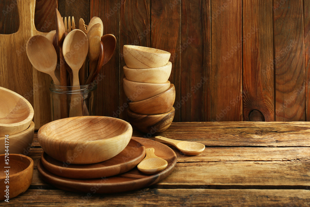 Many different wooden dishware and utensils on table. Space for text