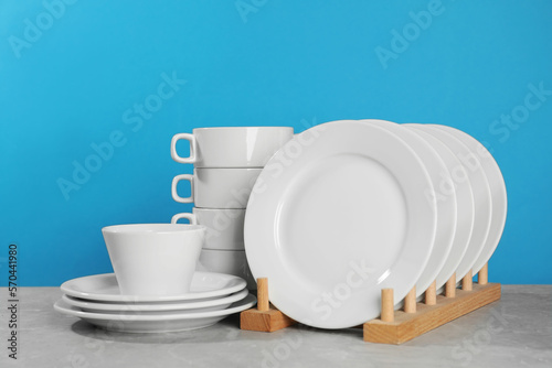 Set of clean tableware on grey table against light blue background
