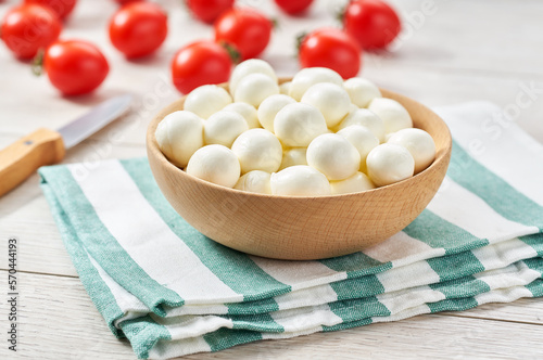 baby mozzarella cheese balls with cherry tomatoes on a kitchen table.