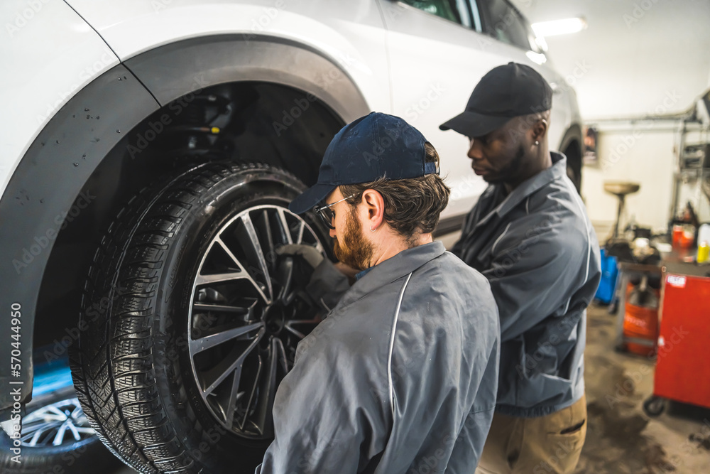 medium back shot of two mechanics changing the wheel on a car, car repair shop. High quality photo medium back shot of two mechanics changing the wheel on a car, car repair shop. High quality photo
