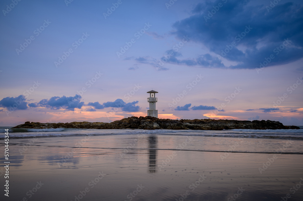 The lonely lighthouse on the rock with evening sun.