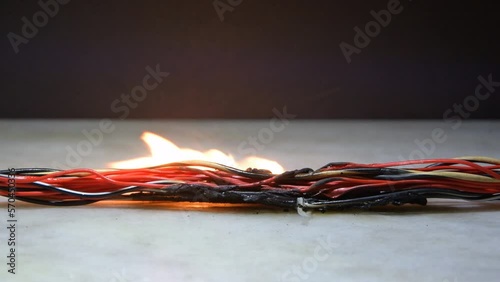 The melted electric wires burn, smoke and go out on a dark background. Short circuit in twisted wires. Flames, sparks and smoke.