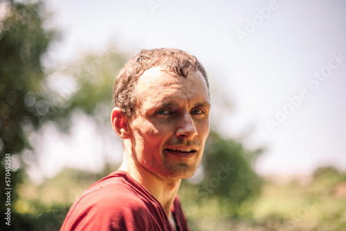 Portrait of happy tired man standing in the garden during summer heat. Farmer at work