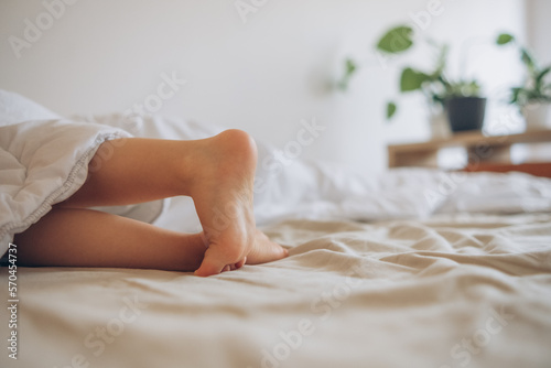 Children's legs stick out from under the warm blanket