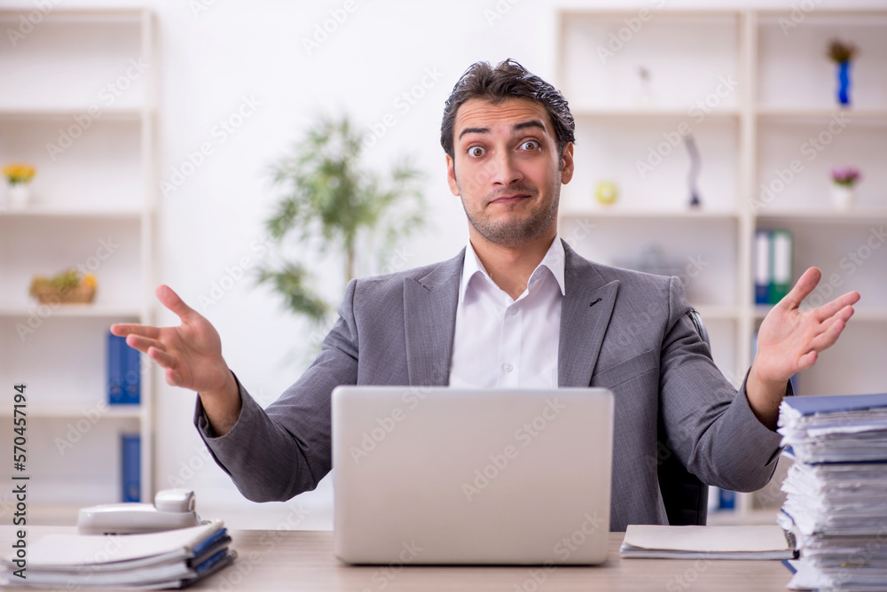 Young male employee and too much work in the office Young male employee and too much work in the office