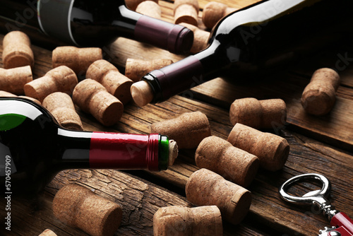 Fotografija Bottles with wine, corkscrew and corks on wooden table